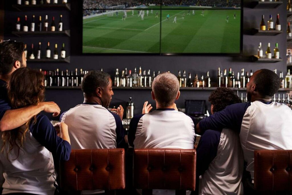 Clientes do bar sentados assistindo às Olimpíadas em Orlando na TV.