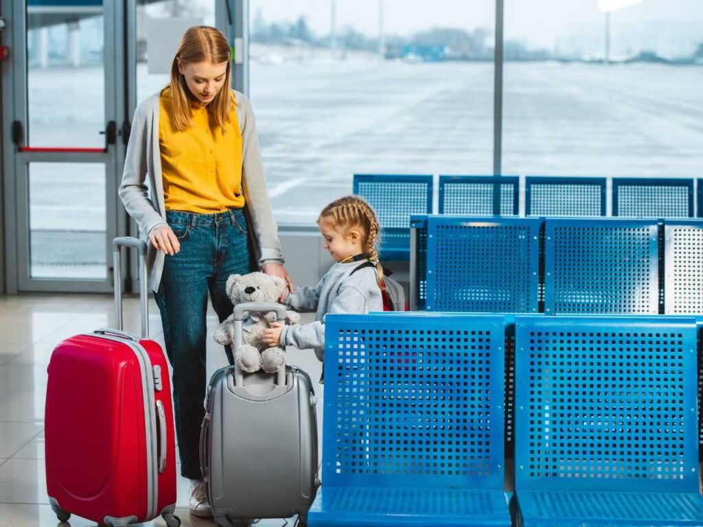 Mulher com malas próxima de criança com idade para viajar sozinha.