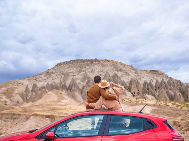 Casal abraçados em cima do carro durante a road trip