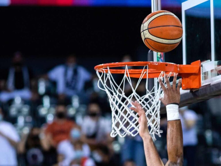 Jogador enterrando a bola de basquete na cesta