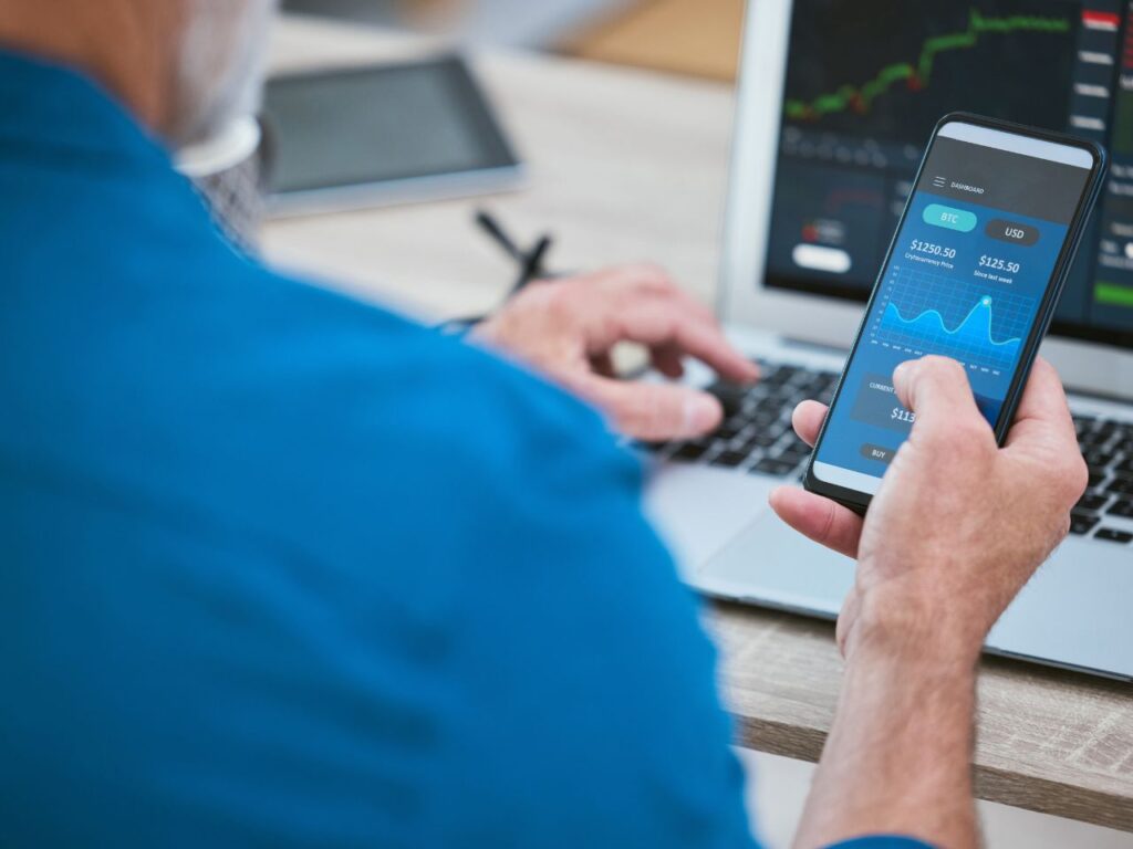 Homem acessando conta do trader pelo app.