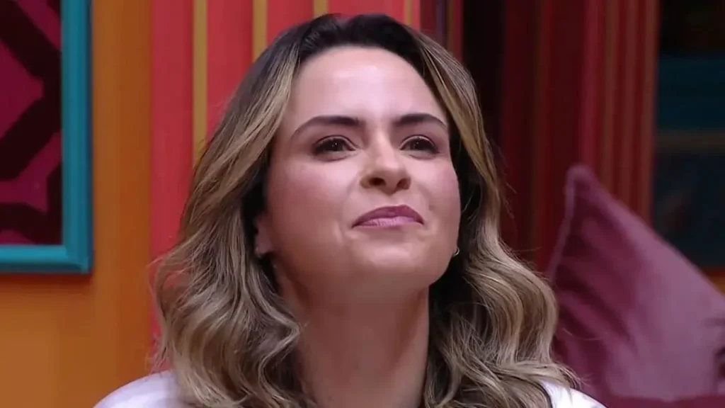 Retrato da jornalista e influenciadora Ana Paula Renault sorrindo durante sua participação em um reality show, com fundo colorido e vibrante.