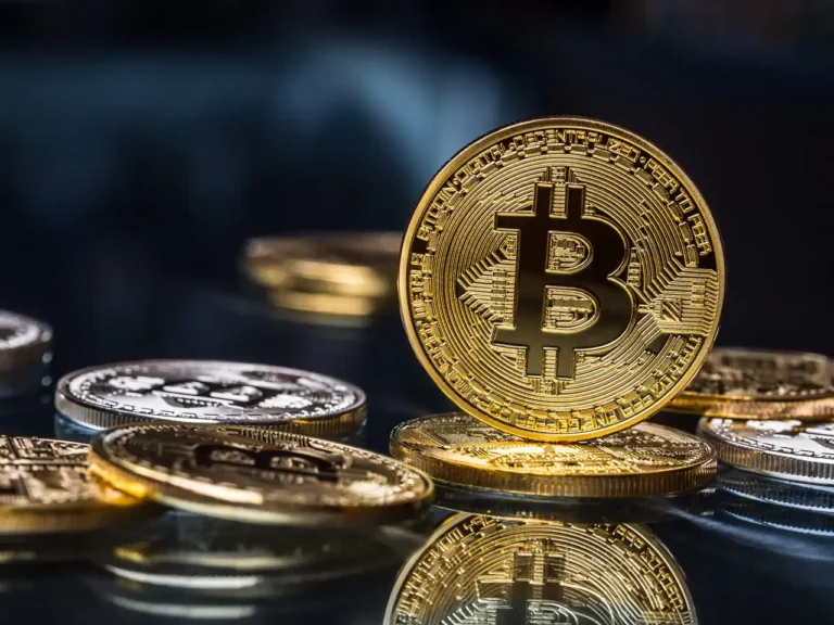 Moedas físicas de Bitcoin douradas sobre superfície reflexiva, ilustrando guia explicativo de como declarar bitcoin no imposto de renda.