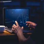 Homem analisa gráficos de investimentos no notebook à noite, buscando os melhores etfs brasileiros abril de 2026 para compor sua carteira.