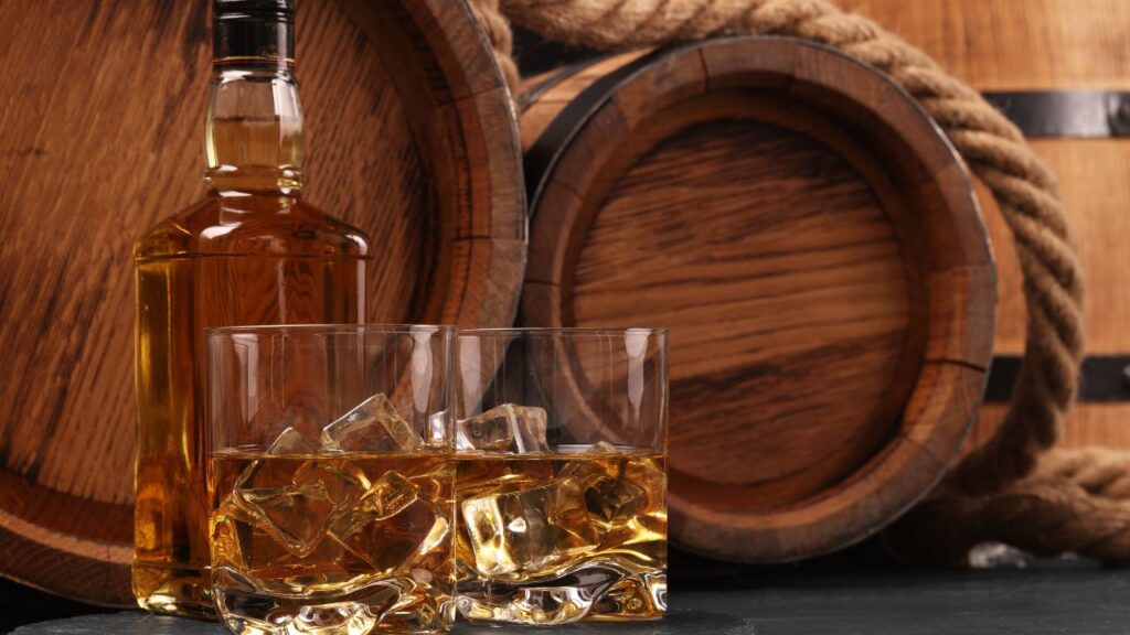 Barris de carvalho perto de uma garrafa de whisky Macallan